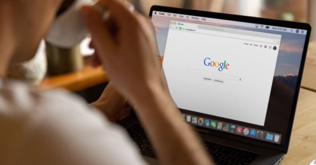 Person on laptop, on Google, with a cup of tea/coffee in hand